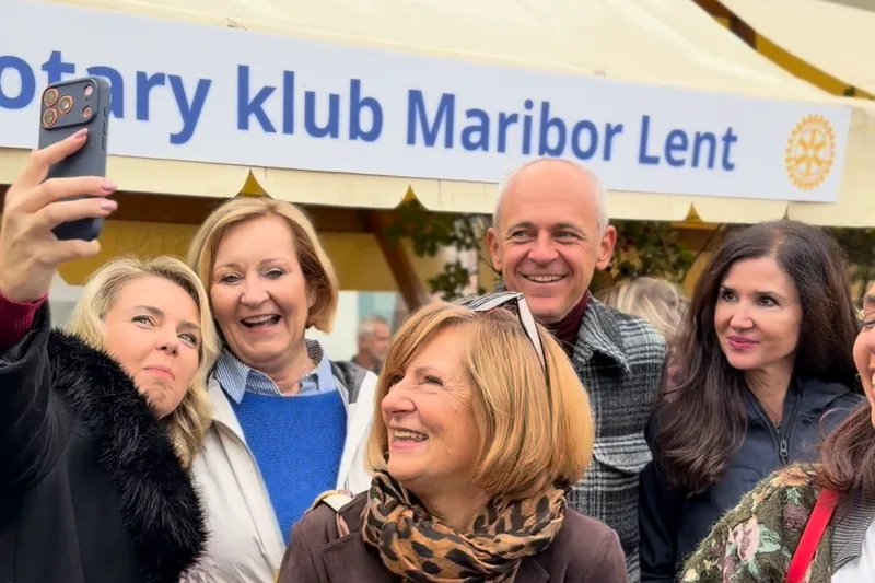 Skupinska fotografija ob stojnici z napisom Rotary klub Maribor Lent.